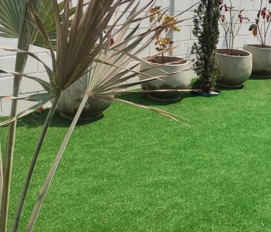 Grama sintética instalada em área externa com vasos de plantas.
