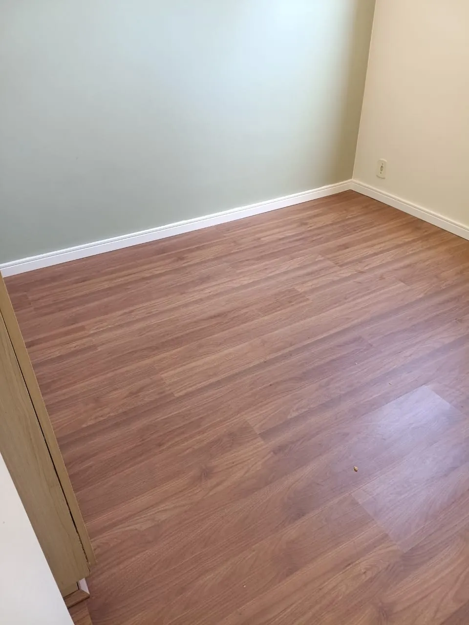 Ambiente com piso de aspecto amadeirado em tom mel e paredes claras.